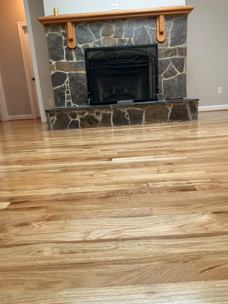 Refinished natural oak flooring in a living room with a stone fireplace
