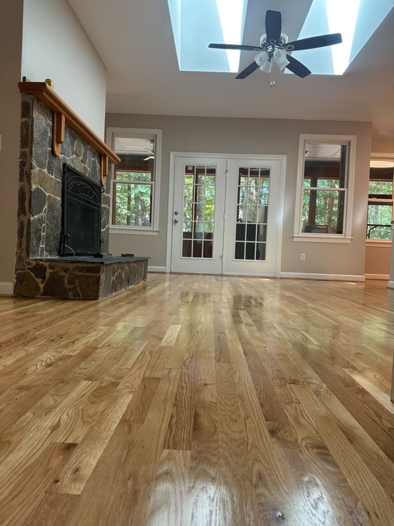 Open living area with refinished oak flooring, skylights and stone fireplace